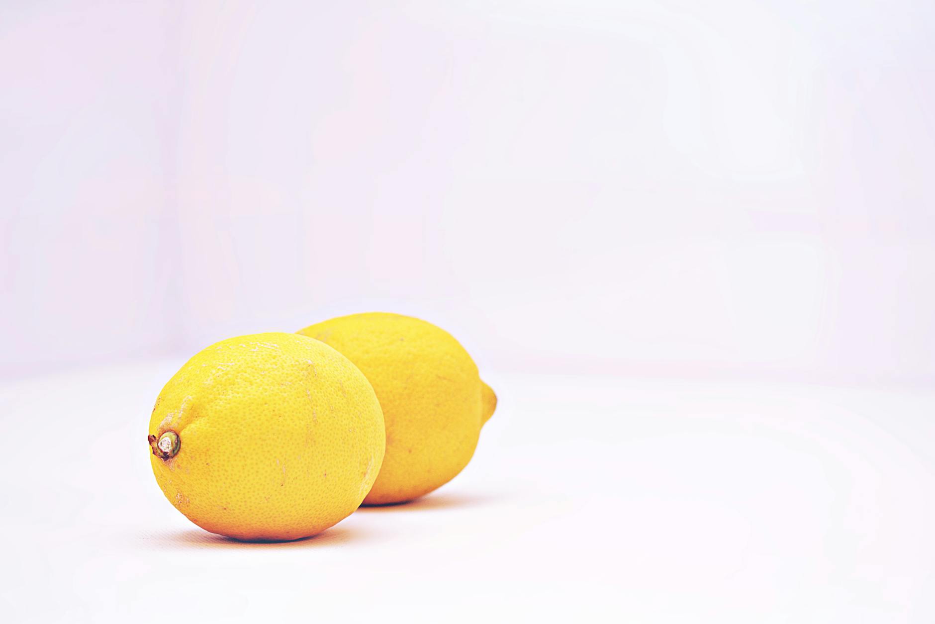 A hand holding an orange vibrator against a minimalistic purple backdrop