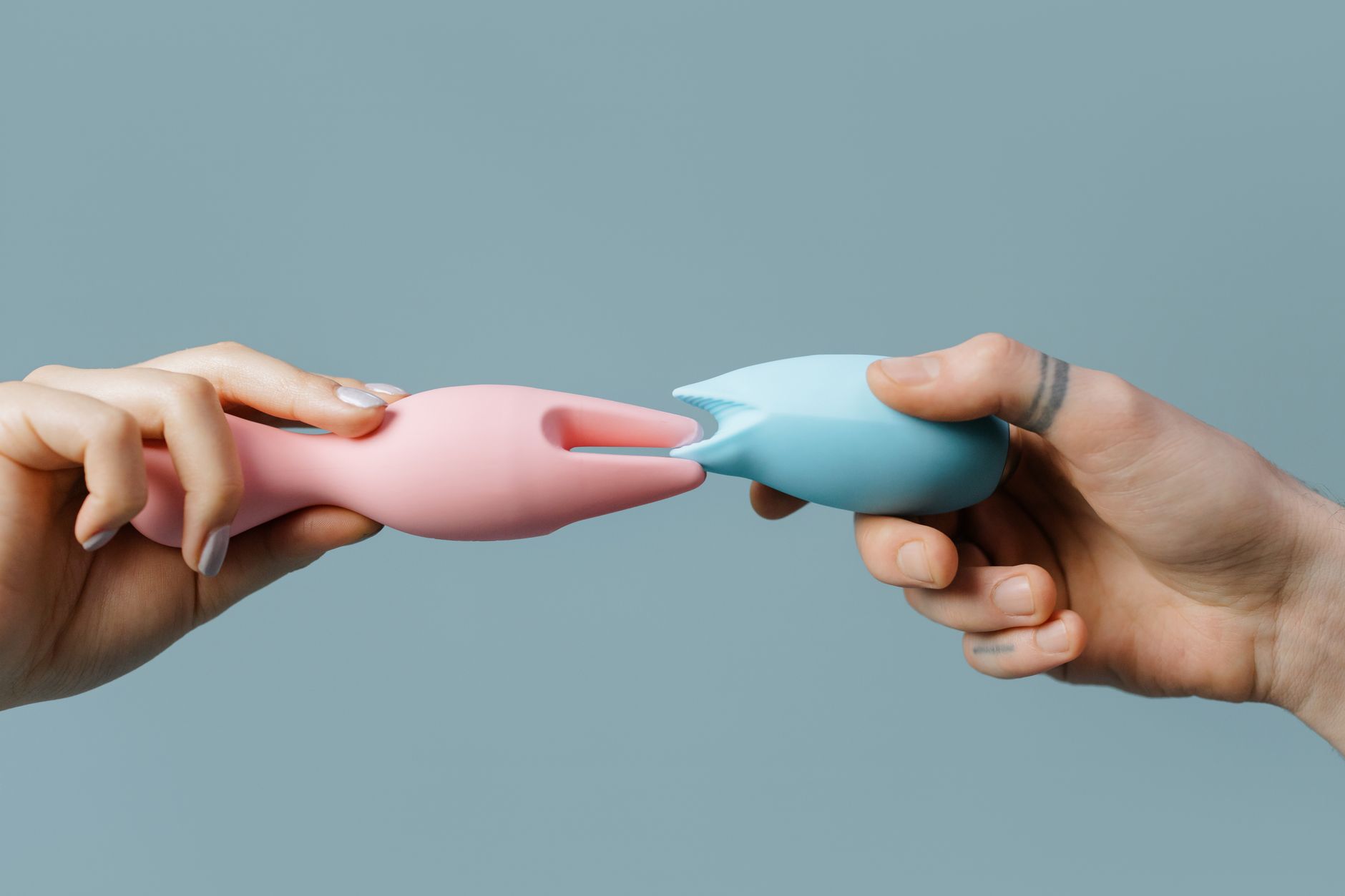 A young couple standing together indoors, holding a blue vibrator, symbolizing modern intimacy